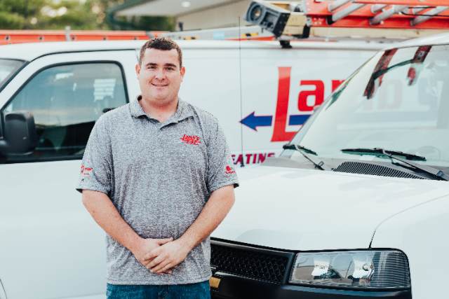Lambs Heating And Air Employee Standing Next To Company Van Lambs Heating And Air Employee Standing Next To Company Van